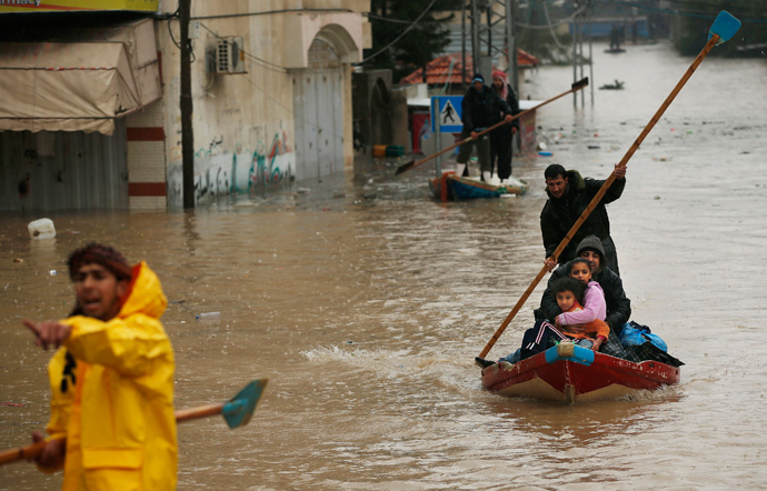 A member of the Palestinian civil defense paddles a boat as he evacuates a man and his children after their house was flooded with rainwater on a stormy day in the northern Gaza Strip December 14, 2013. (Reuters / Mohammed Salem)