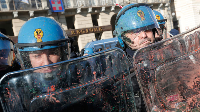Police officers protect themselves with their shields as protesters throw paint bombs during a protest by students against the local government in downtown Turin on December 14, 2013.(AFP Photo / Marco Bertorello)