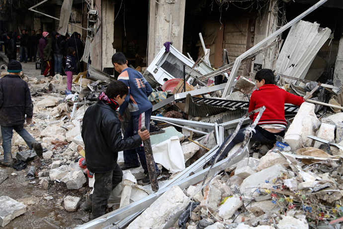 Boys are seen near debris after what activists said was an air strike from forces loyal to Syria's President Bashar al-Assad in Aleppo December 18, 2013. (Reuters / Ahmad Othman)