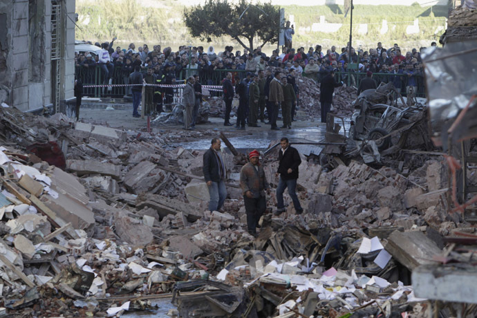 People walk near debris after an explosion near the Building of the Directorate of Security in Egypt's Nile Delta town of Dakahlyia, about 120 km (75 miles) northeast of Cairo December 24, 2013. (Reuters/Mohamed Abd El Ghany)