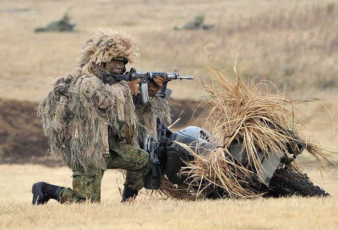 A camouflaged member of Japanese Ground Self Defense Forces' airbourne troops holds an automatic rifle during the new year exercise in Narashino in Chiba prefecture, suburban Tokyo on January 12, 2014 (AFP Photo / Yoshikazu Tsuno)