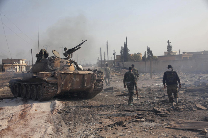 Forces loyal to Syria's President Bashar al-Assad hold their weapon as they stand near a tank in Tel Hasel, Aleppo province after capturing it from rebels November 15, 2013. (Reuters/George Ourfalian)