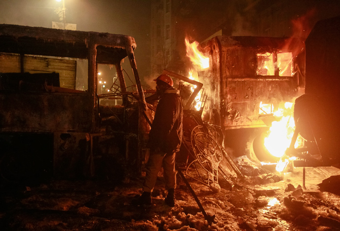 A protester looks at vehicles burnt after clashes with Ukrainian riot police in Kiev January 20, 2014. (Reuters / Gleb Garanich)