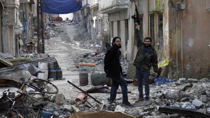 A Free Syrian Army fighter gestures with his gun while he poses for a photograph amid damages in the besieged area of Homs January 19, 2014. (Reuters/Thaer Al Khalidiya)
