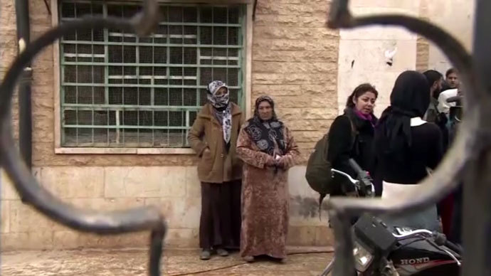 Refugees returning to a village just outside Aleppo, after the Syrian army took control. Screenshot from RT video