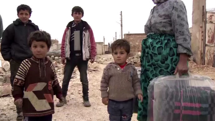 Refugees returning to a village just outside Aleppo, after the Syrian army took control. Screenshot from RT video