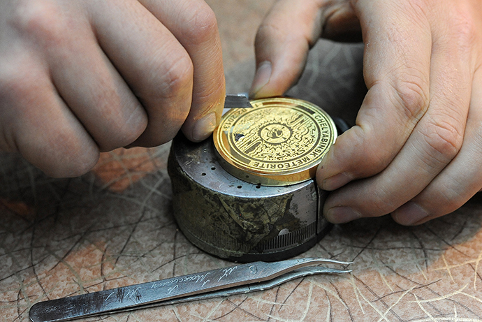 Producing souvenir Olympic medals with fragments from the meteorite in Chelyabinsk at the MAOK art workshop in Zlatoust. (RIA Novosti / Aleksandr Kondratuk)