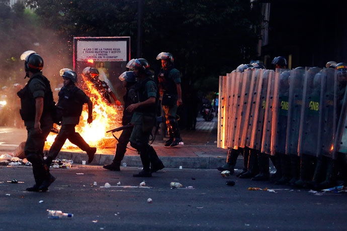 Riot police walk past a barricade of burning garbage during a protest against Venezuela's President Nicolas Maduro's government in Caracas February 12, 2014. (Reuters / Carlos Garcia Rawlins)