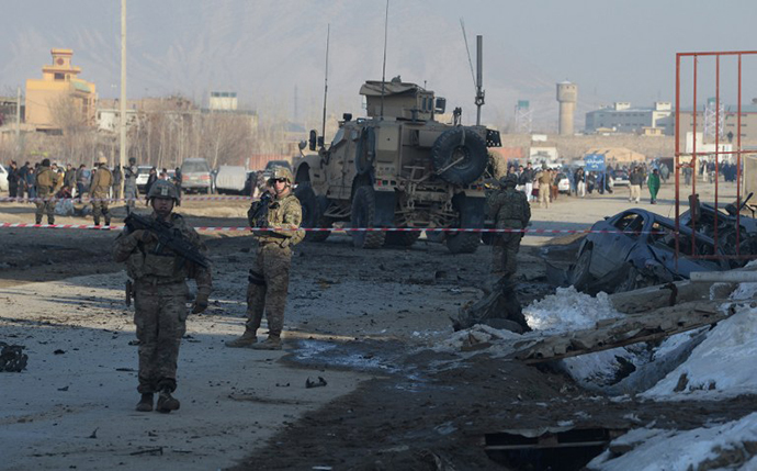 US soldiers, part of the NATO-led International Security Assistance Force (ISAF), stand near a damaged vehicle at the site of a car bomb in the Pol-e-Charkhi area of Kabul on February 10, 2014. (AFP Photo / Shah Marai)