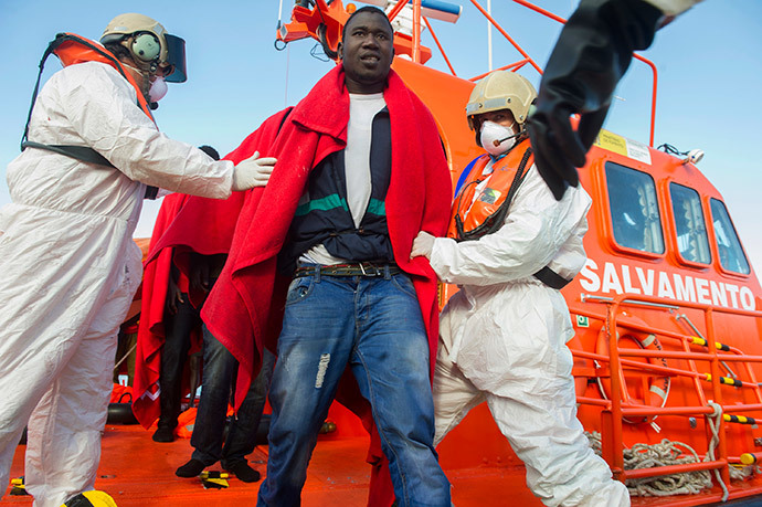 Members of the Spanish emergency services help a would-be immigrant to disembark a coastguard vessel at Tarifa's harbour after 17 would-be immigrants were rescued in the Straight of Gibraltar on November 25, 2013. (AFP Photo / Marcos Moreno)