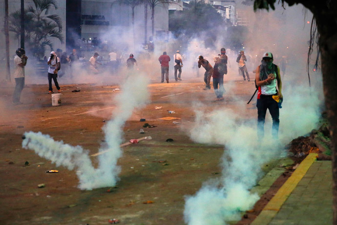 Opposition demonstrators walk through tear gas and throw stones against riot police during a protest against President Nicolas Maduro's government in Caracas February 15, 2014. (Reuters / Carlos Garcia Rawlins)