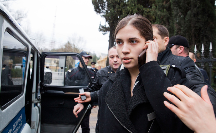 A members of Russian punk group Pussy Riot, Nadezhda Tolokonnikova, speaks by her cell phone, as she is escorted to a police car after being detained in the Adler district of Sochi, on February 18, 2014. (AFP Photo / Evgeny Feldman)