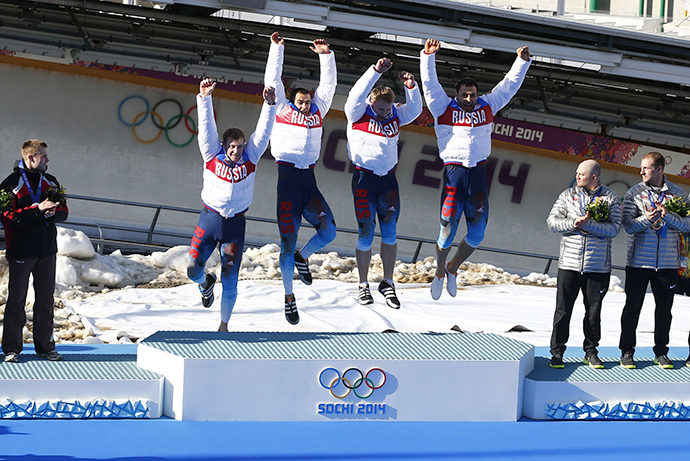 First placed Russia's pilot Alexander Zubkov (5th L to 8th L), Alexey Negodaylo, Dmitry Trunenkov and Alexey Voevoda jump on the podium, as second placed Latvia's pilot Oskars Melbardis (L to 4th L), Daumants Dreiskens, Arvis Vilkaste, Janis Strenga, and (4th R to R) third placed pilot Steven Holcomb of the U.S., with his team mates Curtis Tomasevicz, Steven Langton and Christopher Fogt, look on during the medal ceremony for the four-man bobsleigh event of the Sochi 2014 Winter Olympic Games at the Sanki Sliding Center in Rosa Khutor February 23, 2014. (Reuters / Arnd Wiegmann)