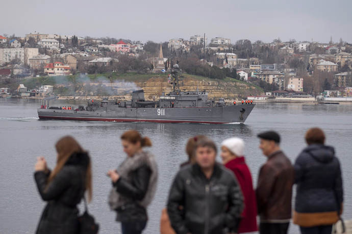 People watch a Russian Navy ship enter the Crimean port city of Sevastopol March 2, 2014 (Reuters / Baz Ratner)