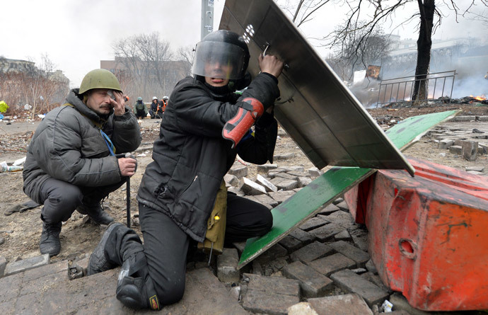 Anti-government protesters take cover as they are under fire reportedly of police sniper during clashes police in the center of Kiev on February 20, 2014.(AFP Photo / Sergei Supinsky)