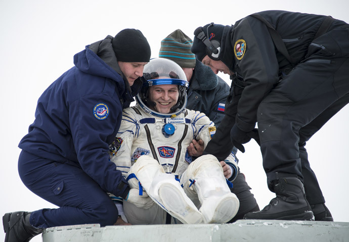 Flight engineer Sergei Ryazansky of Russia is helped out of the Soyuz TMA-10M capsule shortly after the landing in a remote area southeast of the town of Zhezkazgan in central Kazakhstan, March 11, 2014. (Reuters / Bill Ingalls / NASA / Handout via Reuters)