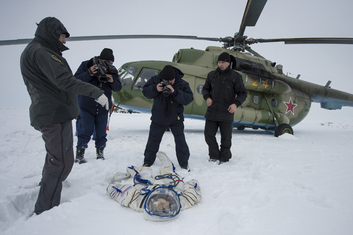 A photographer and an operator document the suit worn byAstronaut Michael Hopkins from NASA after the landing of the Soyuz TMA-10M capsule in a remote area southeast of the town of Zhezkazgan in central Kazakhstan, March 11, 2014. (Reuters / Bill Ingalls / NASA / Handout via Reuters)