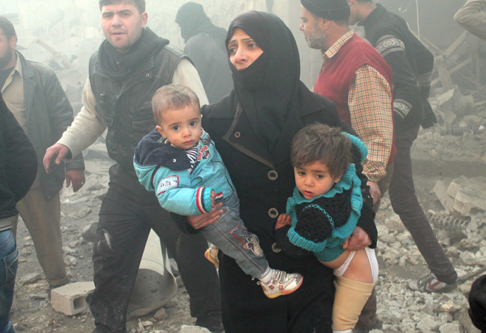 A file photo taken on December 15, 2013 shows a Syrian woman carrying children following airstrikes in northern city of Aleppo. (AFP Photo / Mohammed Al-Khatieb)