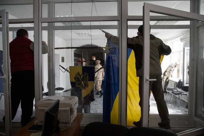A pro-Russian supporter takes down a Ukrainian flag after breaking into the territory of the naval headquarters in Sevastopol, March 19, 2014. (Reuters / Baz Ratner)