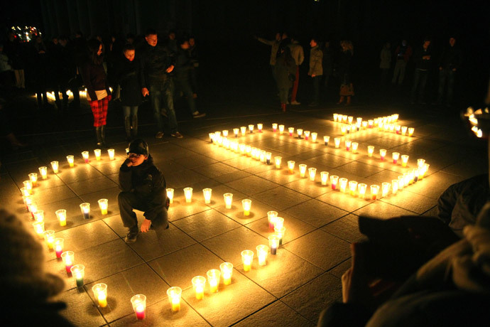 People attend a candle light vigil at Vilnius Cathedral as it stands unlit during Earth Hour in Vilnius on March 29, 2014.(AFP Photo / Petras Malukas)