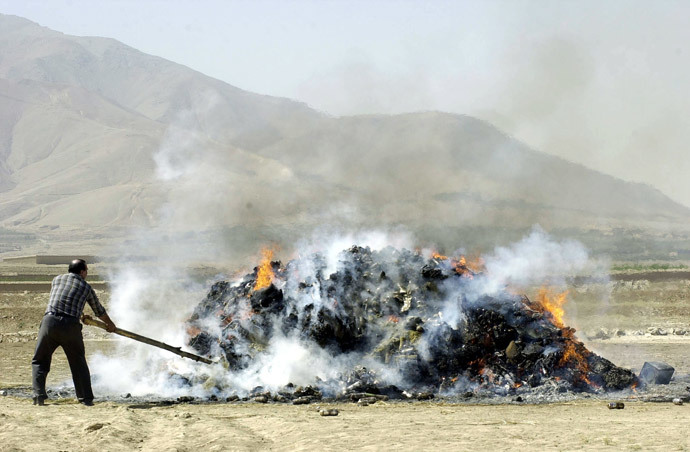 An Afghan official sets fire to seized drugs, including more than 2,5 tons of opium, more than 4 tons of hasish, and some 169 kilos of heroin, outside Kabul, 23 September 2004. (AFP Photo / Shah Marai)