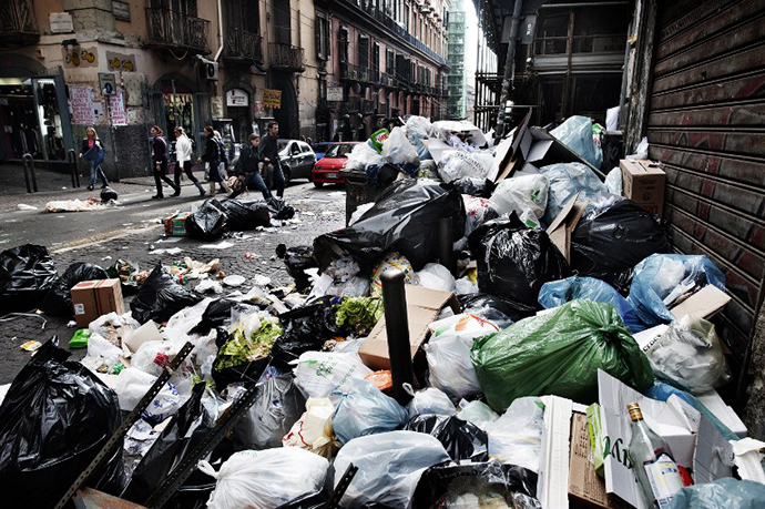 Pedestrians walk by uncollected garbage downtown Naples on October 20, 2010 hours after local residents skirmished with riot police and set a bus alight near Naples. (AFP Photo / Roberto Salomone)