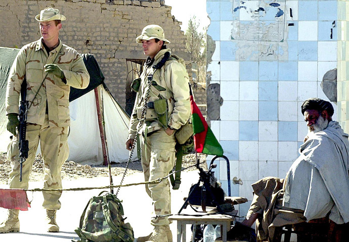 Two US Marine personnel stand alert while an Afghan soldier sits besides them on the main gate of Kandahar airport 22 January 2002. (AFP Photo / Banaras Khan)