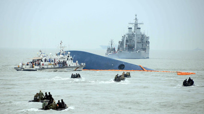 Coast guard members search for passengers near a South Korean ferry (C) that capsized on its way to Jeju island from Incheon, at sea some 20 kilometres off the island of Byungpoong in Jindo on April 17, 2014. (AFP Photo / Ed Jones)