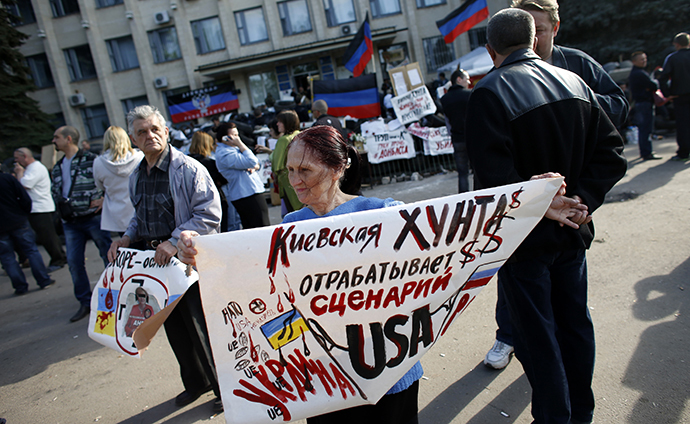 A woman holds a sign outside town administration building in Kramatorsk, eastern Ukraine. The sign reads "The Kiev junta carries out the U.S. scenario". (Reuters / Marko Djurica)