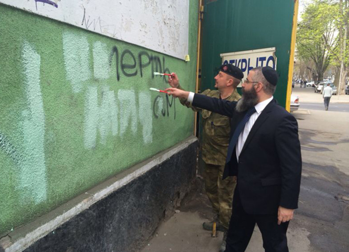 Rabbi Avraham Wolf and UNA-UNSO commander Valery Zagorodny remove anti-Semitic writings. Photo courtesy of the Chabad Odessa Jewish community.