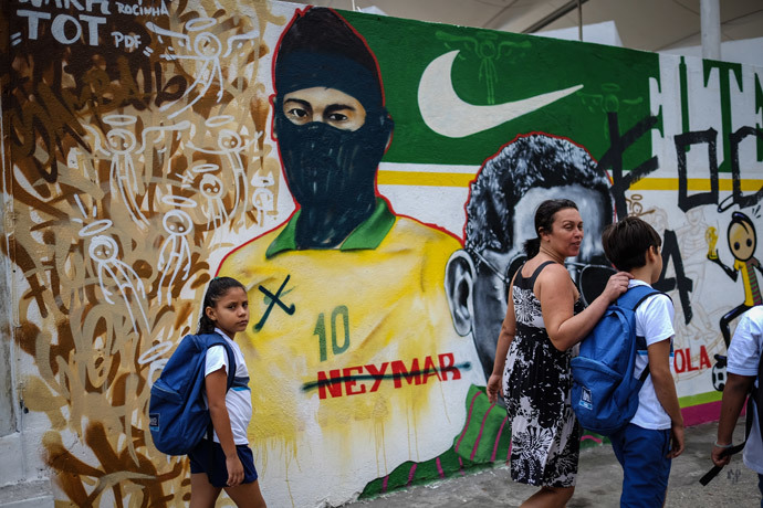 People walk past a vandalized graffiti depicting Brazilian national footballer Neymar with a hood used by members of the anarchist group known as Black Bloc which is against of the FIFA World Cup Brazil 2014 football tournament, in Rio de Janeiro, Brazil, on May 27, 2014. (AFP Photo / Yasuyoshi Chiba)