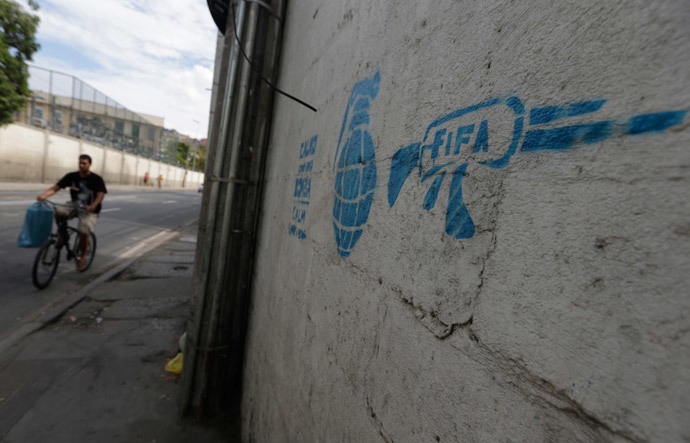 A man rides his bike past a graffiti referencing the 2014 World Cup in Rio de Janeiro May 23, 2014. (Reuters / Ricardo Moraes)