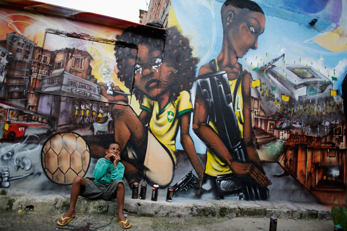 Ryan, 9, eats in front of graffiti painted by members of OPNI, in reference to the 2014 World Cup, in the Vila Flavia slum of Sao Paulo May 28, 2014. (Reuters / Nacho Doce)