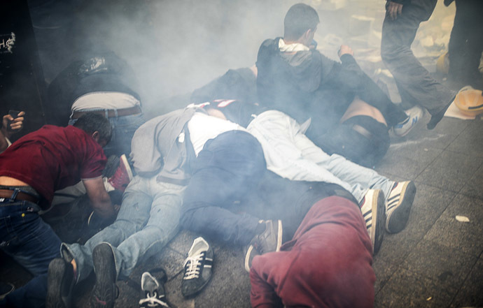 Injured protesters lie on the ground as Turkish riot police officers fire tear gas to disperse demonstrators gathered on the central Istoklal avenue near Taksim square in Istanbul, on May 31, 2014, as the police blocked access to the square during the one year anniversary of the Gezi park and Taksim square demonstrations. (AFP Photo/Bulent Kilic)
