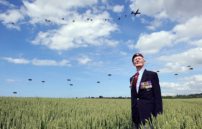 British WWII veteran Frederik Glover stands in a corn field as soldiers parachute down during a D-Day commemoration in northern France on June 5 2014. (AFP Photo / Thomas Bregardis)