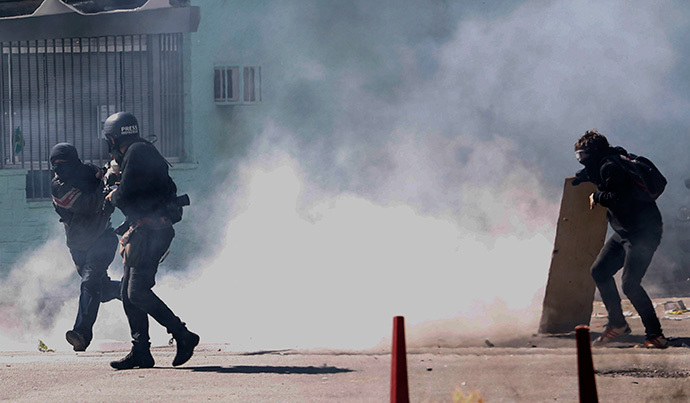 Demonstrators and a photographer run from tear gas shot by riot police during an anti-World Cup protest on the morning the Brazilian mega-city hosts the tournament's opening match, in Sao Paulo on June 12, 2014. (AFP Photo / Miguel Schincariol)