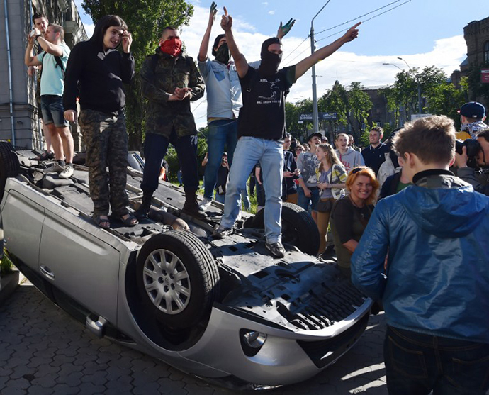 Demonstrators stand on an overturned car during a rally against the Russian president in front of the Russian embassy in Kiev on June 14, 2014. (AFP Photo / Sergei Supinsky)