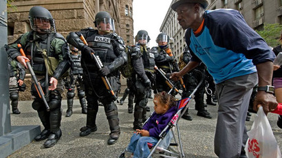 A resident and child pass riot police as they patrol a street during a demonstration against the G20 summit in downtown Pittsburgh, Pennsylvania. (AFP Photo / Paul J. Richards)