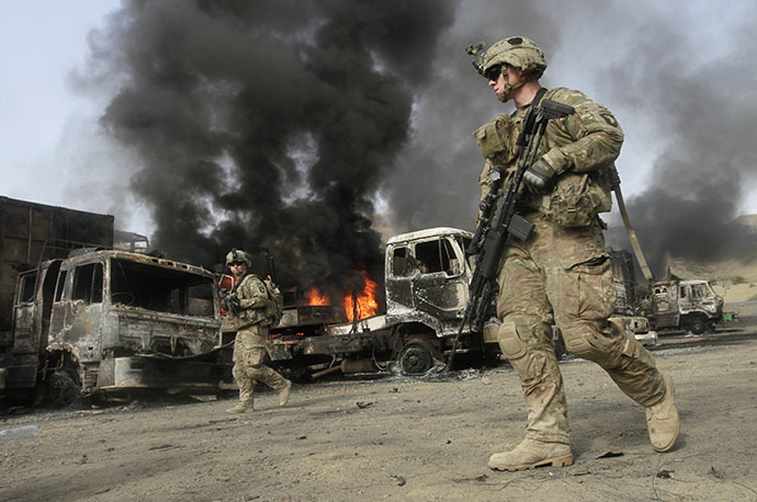 NATO troops walk near burning NATO supply trucks after, what police officials say, was an attack by militants in the Torkham area near the Pakistani-Afghan in Nangarhar Province June 19, 2014. (Reuters / Parwiz Parwiz)