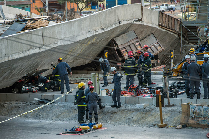 Firefighters and policemen work at the site where several vehicles were crushed by a viaduct that collapsed in Belo Horizonte, Brazil, on July 3, 2014. (AFP Photo/Pedro Duarte)