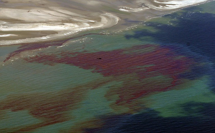 A National Guard Blackhawk helicopter flies over the oil slickas it passes through the protective barrier formed by the Chandeleur Islands, as cleanup operations continue for the BP Deepwater Horizon platform disaster off Louisiana, on May 7, 2010. (AFP Photo / Mark Ralston)