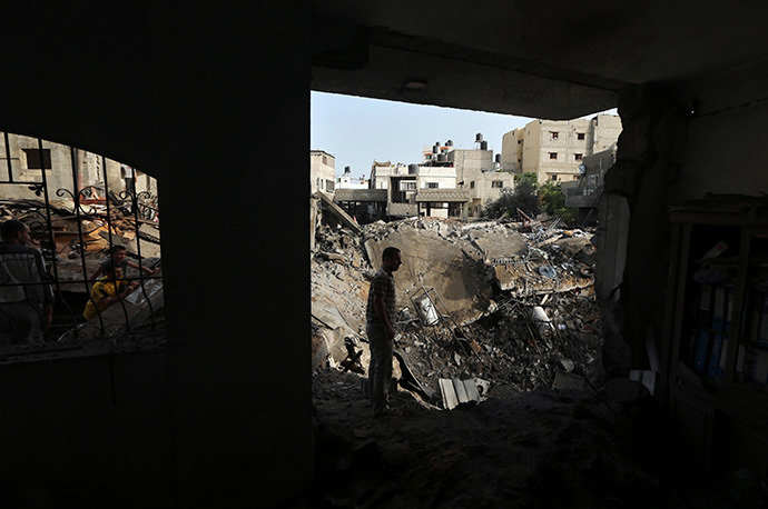 Palestinians survey the rubble of a house which police said was destroyed in an Israeli air strike in the northern Gaza Strip July 12, 2014. (Reuters / Mohammed Salem)