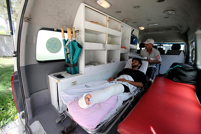 A Palestinian man, whom medics said was wounded in an Israeli air strike, lies on a bed inside an ambulance waiting to cross into Egypt, at the Rafah crossing on the southern Gaza Strip July 12, 2014. (Reuters / Ibraheem Abu Mustafa)