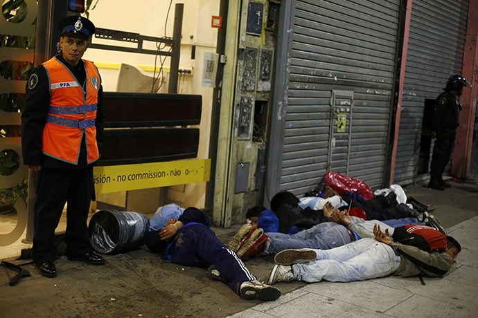 Police stand guard next to people who were detained during riots after Argentina lost to Germany in their 2014 World Cup final soccer match in Brazil, in downtown Buenos Aires July 13, 2014. (Reuters / Ivan Alvarado)