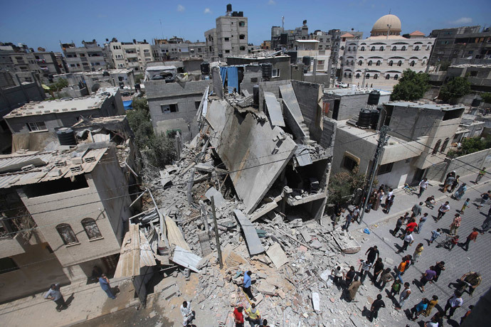 Palestinians gather around the remains of a house, which police said was destroyed in an Israeli air strike, in Rafah in the southern Gaza Strip July 14, 2014.(Reuters / Ibraheem Abu Mustafa)