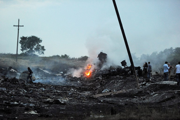 People stand, on July 17, 2014, amongst the wreckages of the malaysian airliner carrying 295 people from Amsterdam to Kuala Lumpur after it crashed, near the town of Shaktarsk. (AFP Photo / Dominique Faget)