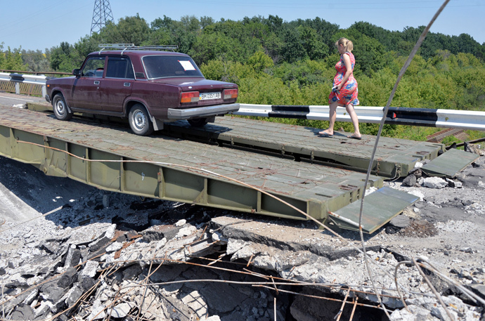 People cross a damaged bridge with their car on August 1, 2014 near the village of Debaltseve, in the Donetsk region, eastern Ukraine. (AFP Photo / Genya Savilov)