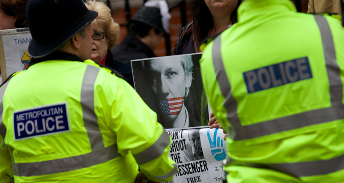 Police stand guard in front of supporters of WikiLeaks founder Julian Assange who are standing with banners outside the Ecuadorian Embassy in London on June 19, 2014 (AFP Photo / Andrew Cowie)