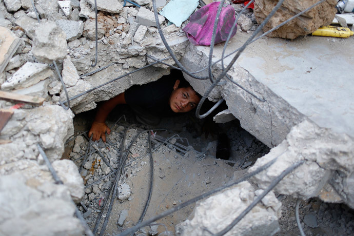 A boy looks at the camera as he tries to salvage some belongings from the ruins of his family's apartment that witnesses say was destroyed by Israeli air strikes in the Shejaia neighbourhood in Gaza City August 12, 2014. (Reuters / Siegfried Modola)