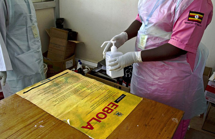 Ugandan medical staff disinfect a desk bearing a poster reading ''Ebola'' at the Entebbe International Airport on August 8, 2014. (AFP Photo / Isaac Kasamani)